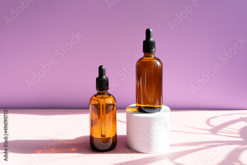 Still life of cosmetic products. Blank  isolated on a powdery pink and lilac background to accommodate your design with sun shadows.