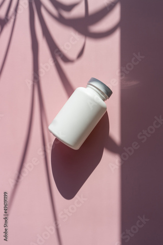  white cosmetic jars on a lilac-pink background with sun shadows. template for cosmetics. still life for a cosmetic article.
