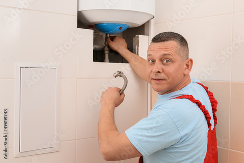 Plumber repairing boiler in...