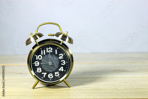 alarm clock showing twelve o'clock on wooden table. lunch time concept