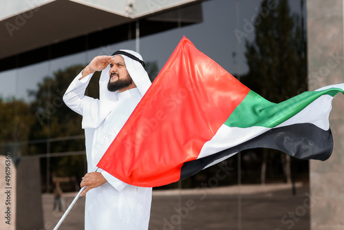 Man in traditional clothes and with the national flag of UAE outdoors
