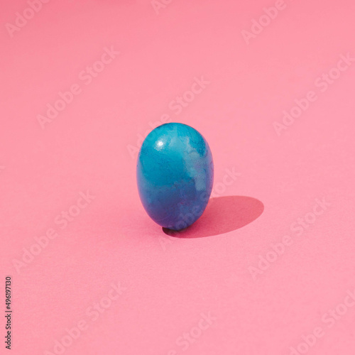 Blue Easter egg against the pink background.Simple and pure
