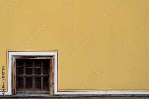 small wooden window on a yellow wall