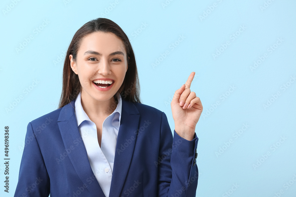Pretty young businesswoman pointing at something on blue background Pretty young businesswoman pointing at something on blue background