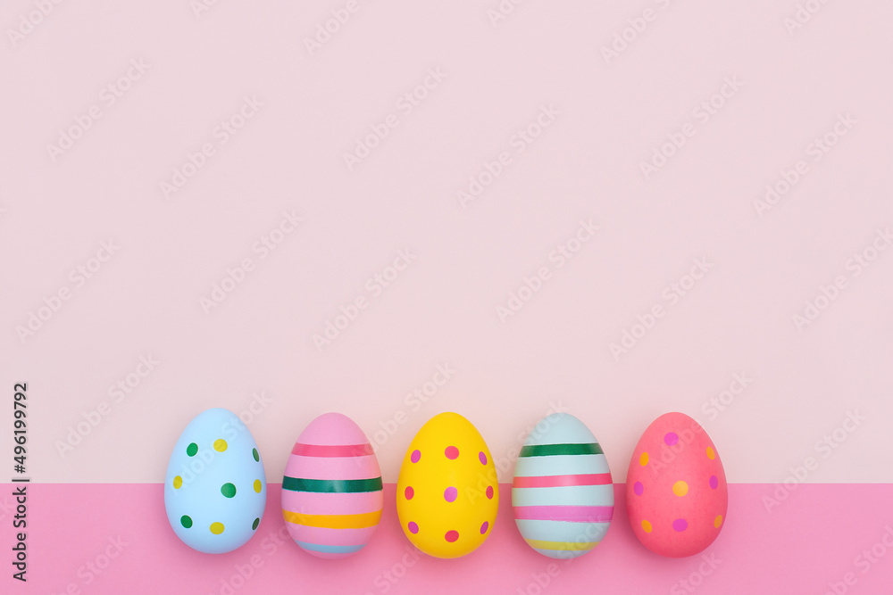 Easter border of bright Easter eggs on two-tones pink background. Multi-colored striped and dotted eggs in a row with copy space.