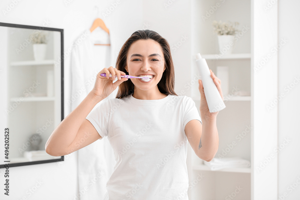 Young woman with paste brushing teeth in bathroom Young woman with paste brushing teeth in bathroom