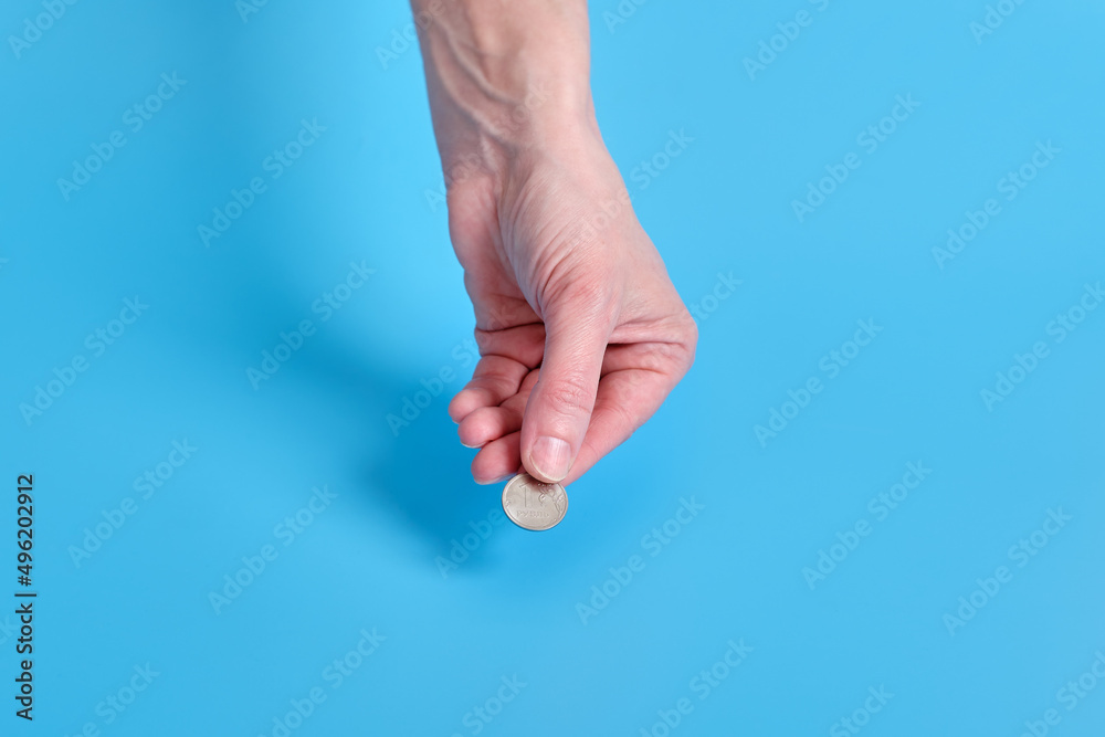 Russian ruble money, coins in a female hand on a blue background. Copy space Russian ruble money, coins in a female hand on a blue background. Copy space