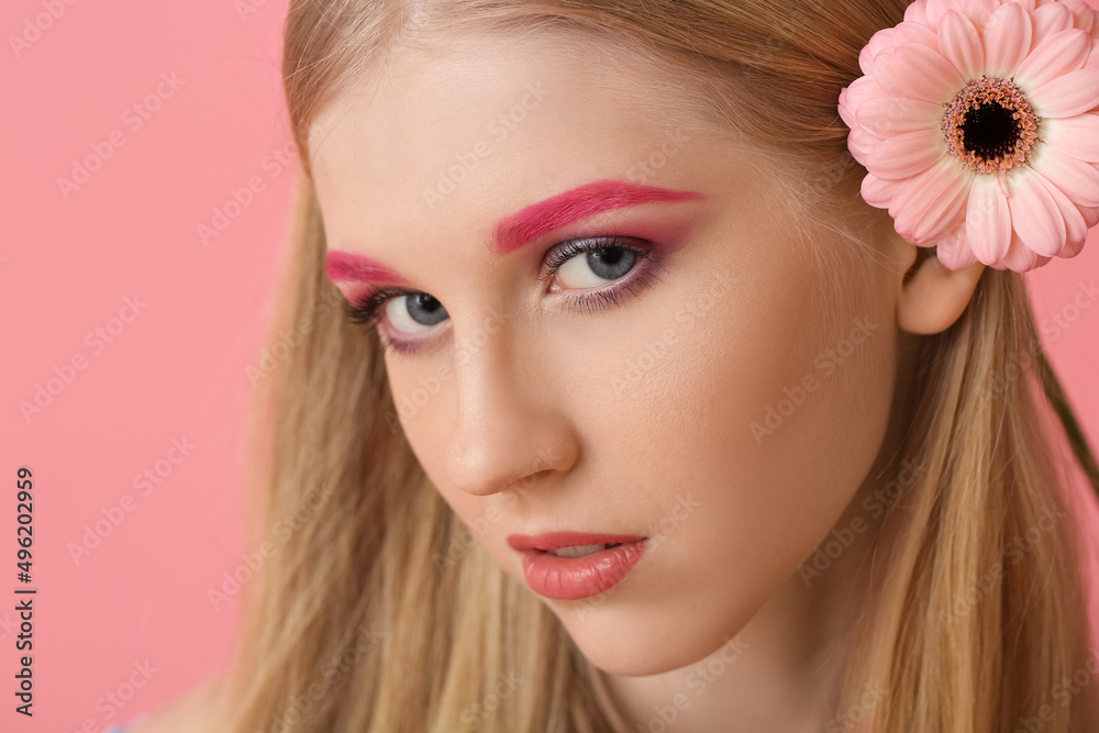 Young woman with creative makeup and gerbera flower on color background Young woman with creative makeup and gerbera flower on color background