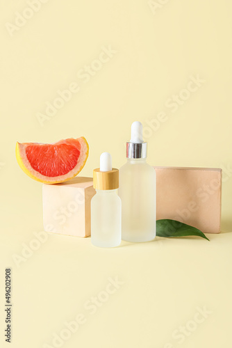 Composition with bottles of essential oil  grapefruit slice and decor on color background