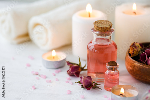 Concept of spa treatment in salon. Natural organic oil  towel  candles as decor. Atmosphere of relax  serenity and pleasure. Anti-stress and detox procedure. Luxury lifestyle. White wooden background