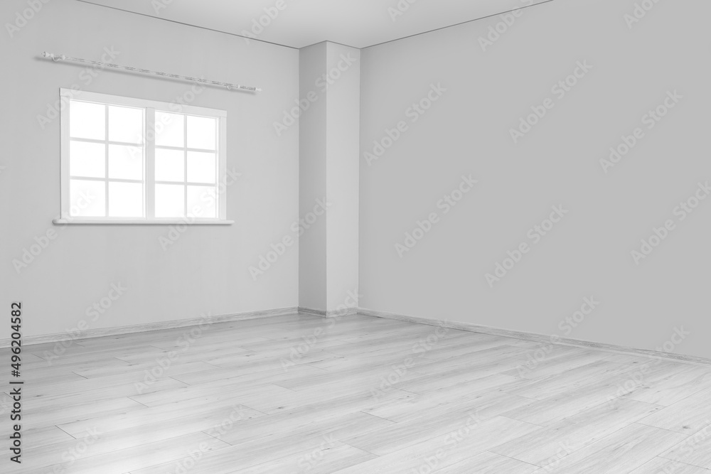 View of big empty room with light walls and window View of big empty room with light walls and window