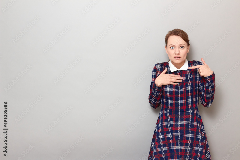 Portrait of unhappy young woman pointing with finger at herself