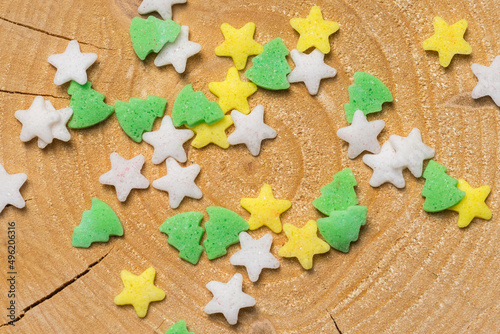 Star and Christmas tree-shaped traditional cake sprinkles on cracked pine tree wood slice
