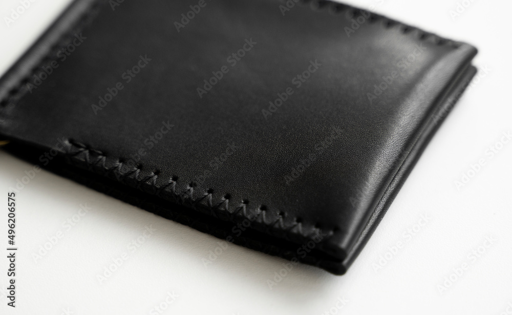 Black men's money clip handmade leather wallet. Empty money clip wallet with a two pockets for cards lies on a white table. Selective focus, copy space. Black men's money clip handmade leather wallet. Empty money clip wallet with a two pockets for cards lies on a white table. Selective focus, copy space.