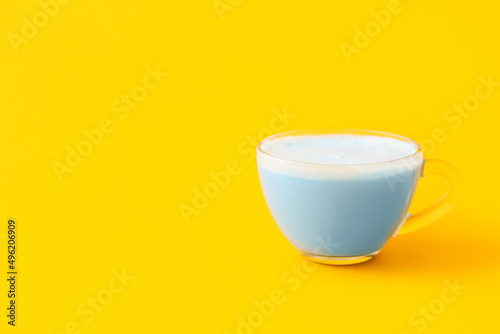 Glass cup of blue matcha tea on yellow background