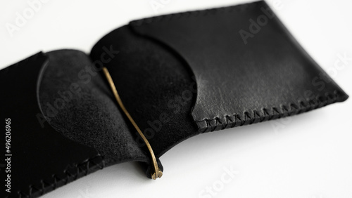 Open black men's money clip handmade leather wallet. Close up. Empty money clip wallet with a two pockets for cards lies on a white table. Selective focus, copy space.