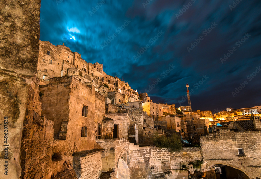 One of the many outer walls and hillsides of homes in the ancient prehistoric city of Matera Italy at night.