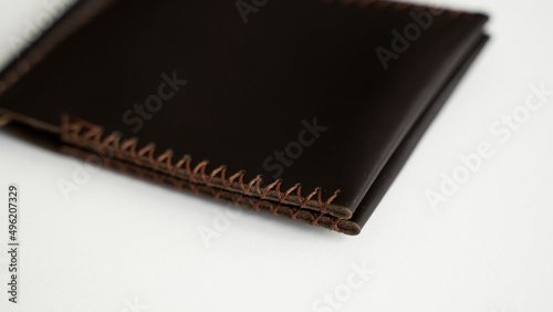 Brown men's money clip handmade leather wallet. Empty money clip wallet with a two pockets for cards lies on a white table. Selective focus, copy space.