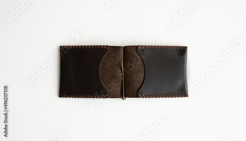 Open brown men's money clip handmade leather wallet. Empty money clip wallet with a two pockets for cards lies on a white table. Selective focus, copy space.