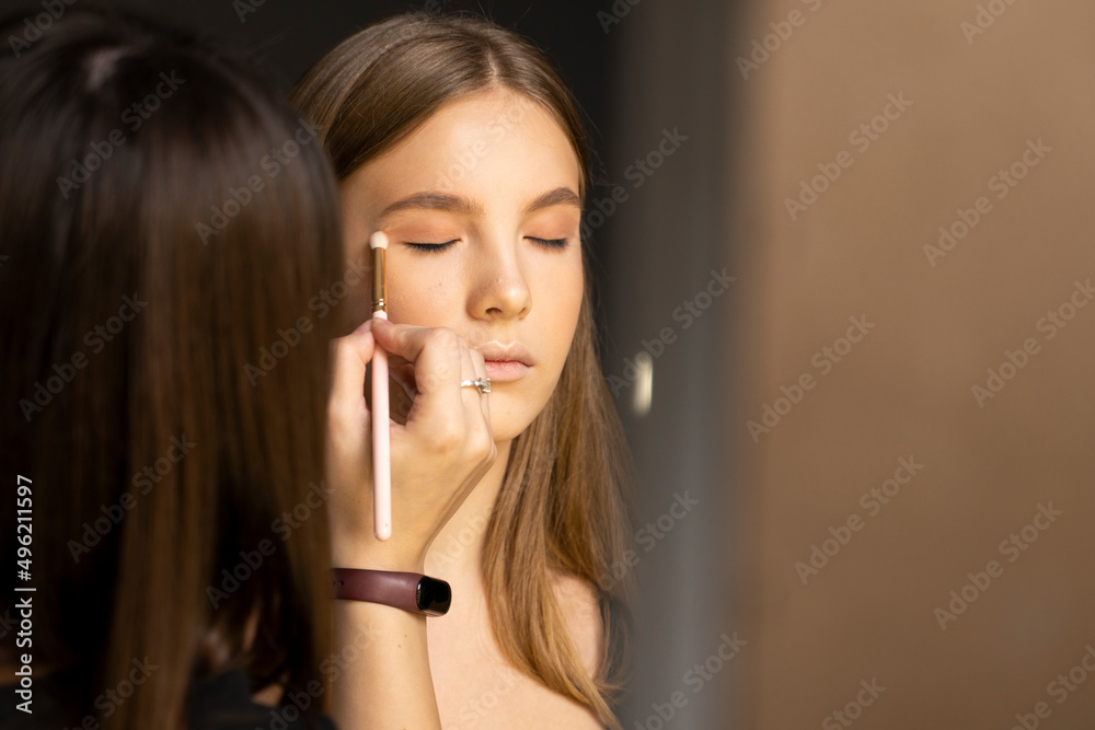 Proffesional make-up artist applying eyeshadow powder on a models eyes in beauty studio. Proffesional make-up artist applying eyeshadow powder on a models eyes in beauty studio.