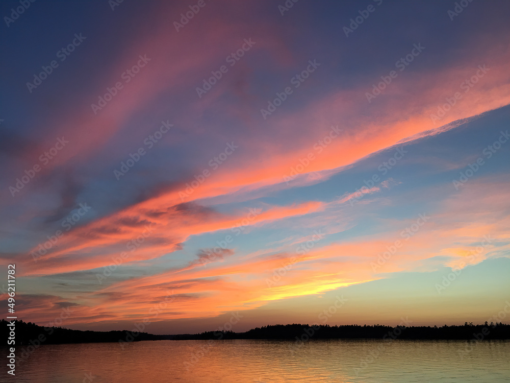 Brilliant sunset over northern Minnesota fishing lake fills sky with colorful clouds and subtle golden hour hues