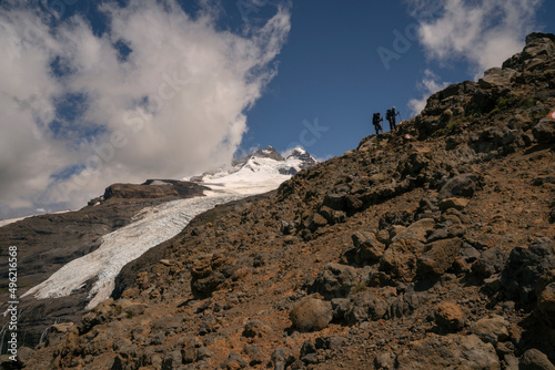 Alpine scenic. View of two hikers climbing up Tronador hill and glacier Castaño Overo in the Andes mountains in Patagonia Argentina. The rocky mountaintop and glacier ice field in a sunny day. 