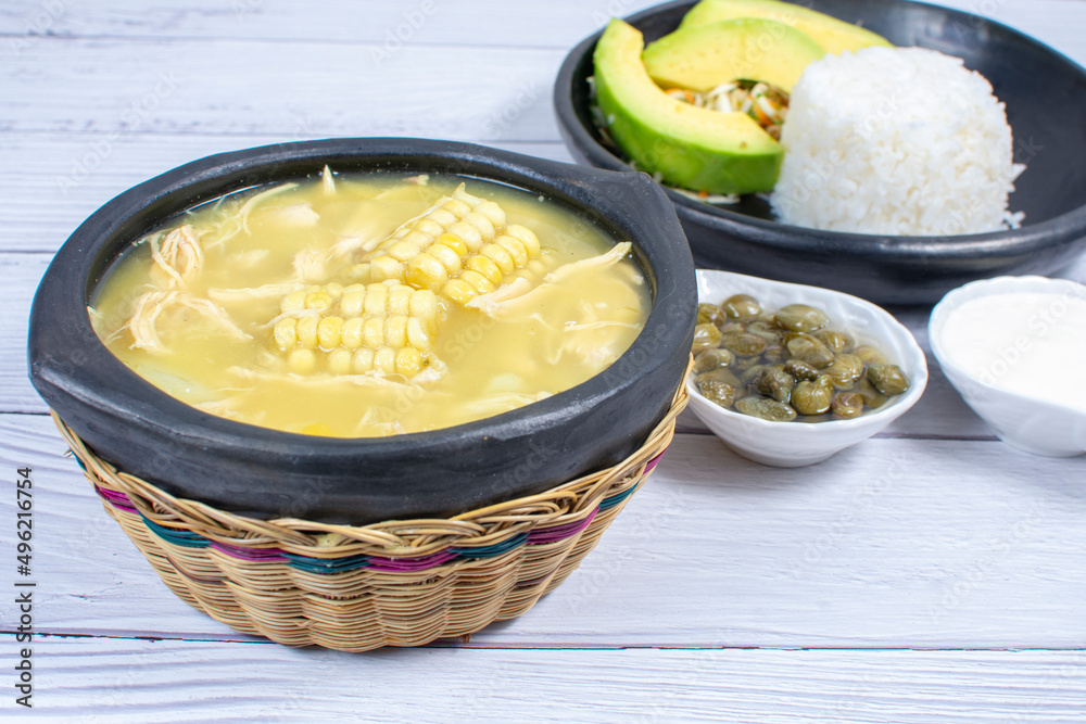 Ajiaco, traditional Colombian food, accompanied by rice, milk cream, avocado, capers and salad