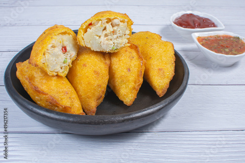 Traditional Colombian snack, chicken empanada with hogao, lemon and sauce