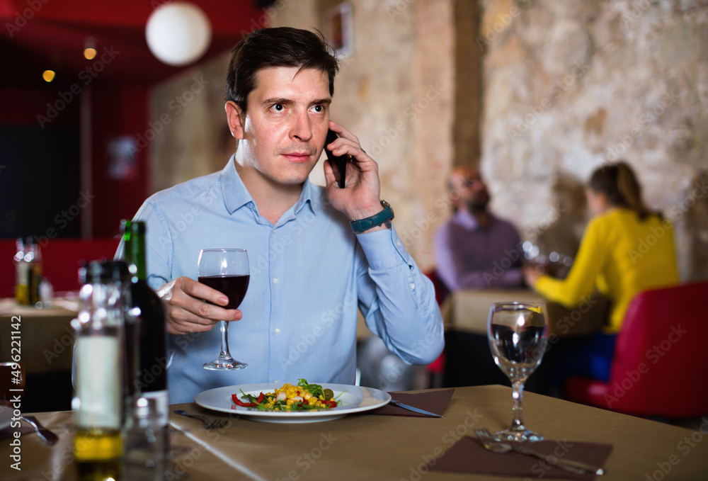 Serious angry unhappy man solving problems on phone while dining in restaurant