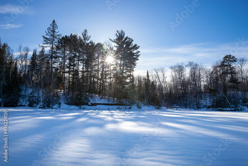 Sun burst in pine trees on a snowy northern Minnesota lake during a winter sunset
