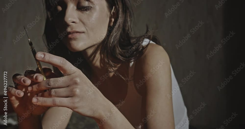 Female drug addict holding up a hypodermic needle and syringe. Female drug addict with running mascara holding up a hypodermic needle and syringe in a close up portrait with copyspace