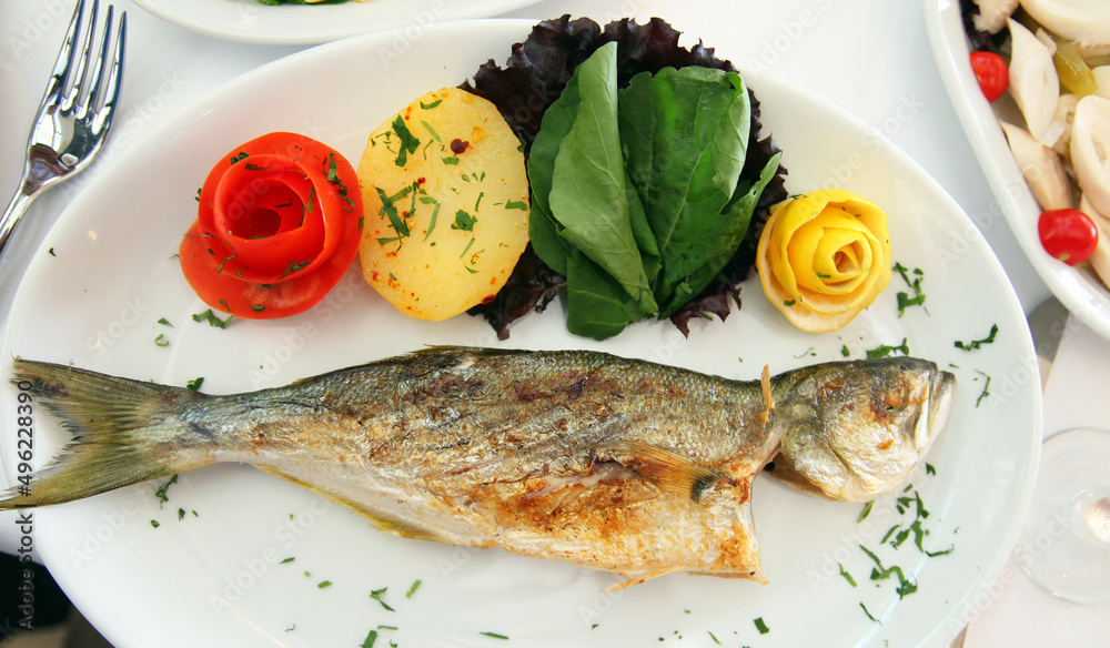 Grilled perch fish (Turkish: Levrek) with potato, lemon and tomato on the dinner plate. Grilled perch fish (Turkish: Levrek) with potato, lemon and tomato on the dinner plate.