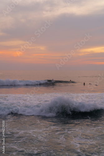 Surfers catch waves at sunset in the ocean. Surfing background