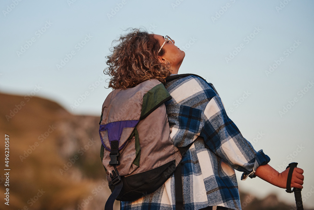 A woman hiking with a backpack and poles at sunset. Selective focus A woman hiking with a backpack and poles at sunset. Selective focus