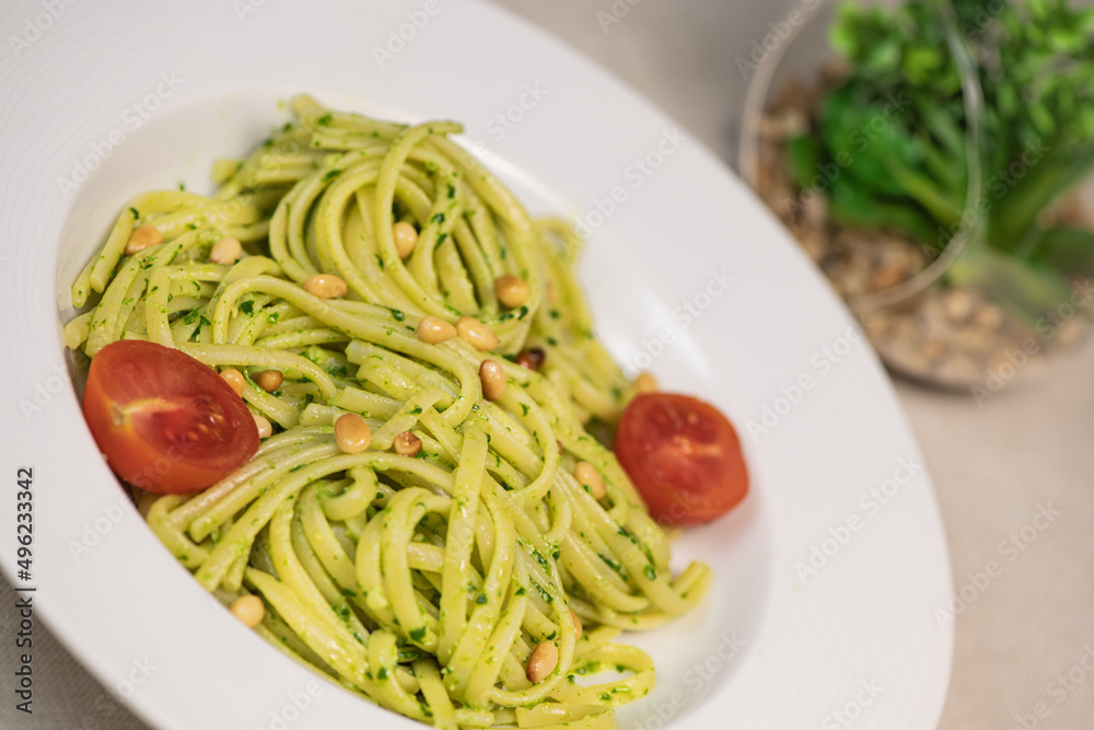 green spinach spaghetti with cheese and tomato on wooden table