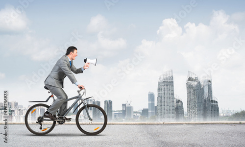 Businessman with megaphone in hand on bike © adam121