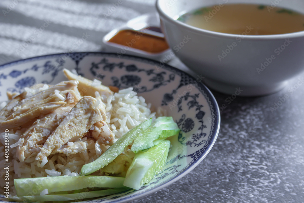 rice steamed with chicken soup served in a Chinese style plate with soy sauce and broth on a gray table