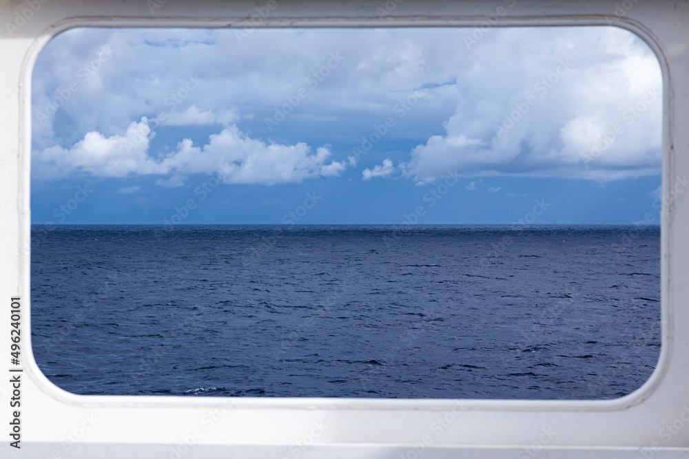 Fototapeta premium Rectangular steel window on a ship overlooking the open sea and sky.