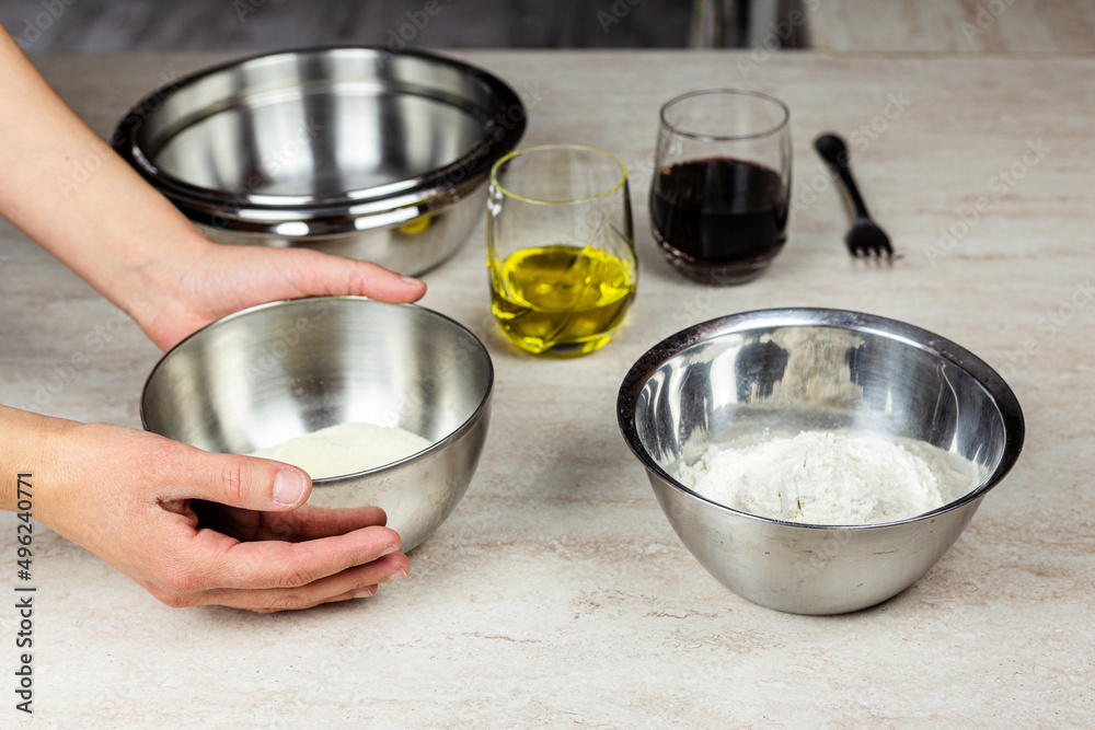 Cooking at home. Ingredients for the preparation of a recipe. Flour, olive oil, wine. Hands taking a bowl Cooking at home. Ingredients for the preparation of a recipe. Flour, olive oil, wine. Hands taking a bowl