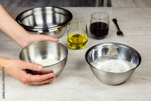 Cooking at home. Ingredients for the preparation of a recipe. Flour, olive oil, wine. Hands taking a bowl