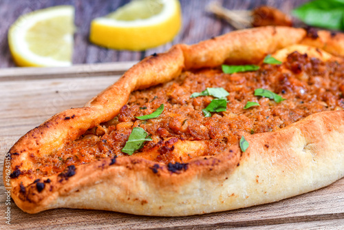 Traditional Turkish cuisine. Baked Pide dish with minced  beef  tomatoes and  herbs on  wooden background.  Turkish pizza pide