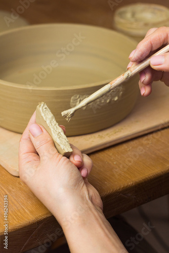 Woman ceramist attaching handle to the pot in pottery class. Potter workshop in ceramic studio