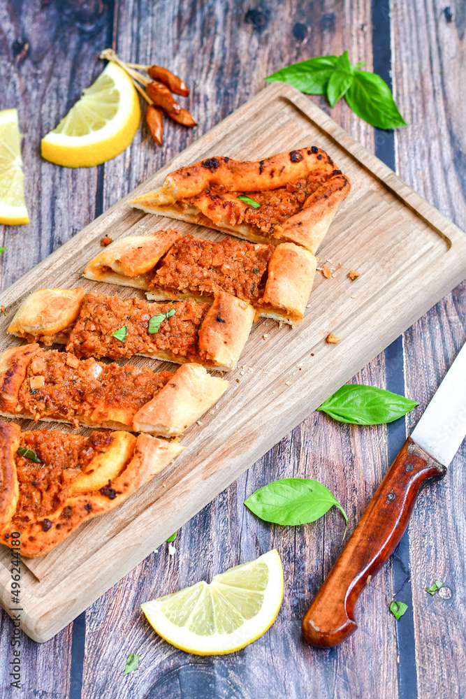 Traditional Turkish cuisine. Baked Pide dish with minced beef, tomatoes and herbs on wooden background. Turkish pizza pide Traditional Turkish cuisine. Baked Pide dish with minced beef, tomatoes and herbs on wooden background. Turkish pizza pide