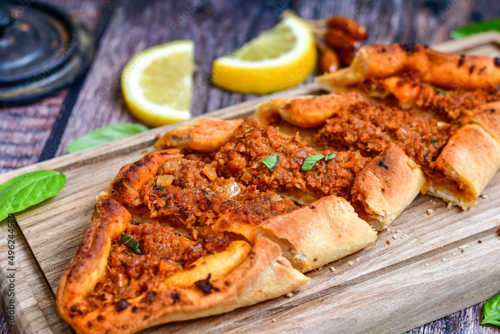  Traditional Turkish cuisine. Baked Pide dish with minced  beef, tomatoes and cheese on  wooden background.  Turkish pizza pide