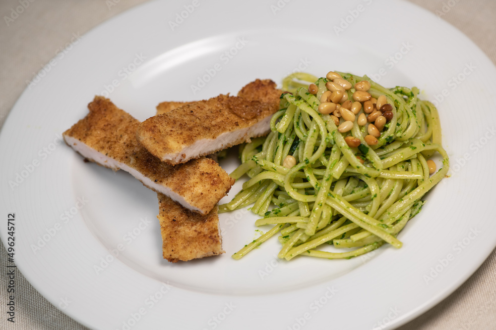 Turkey cutlet and Green spinach spaghetti with cheese and tomato on wooden table. High quality photo