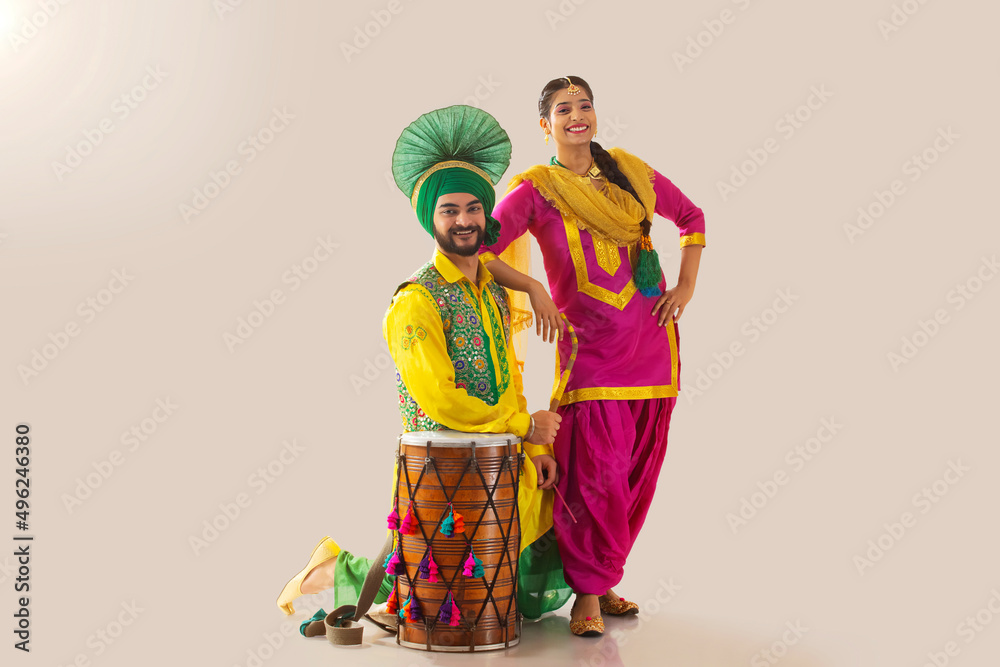 Sikh couple posing with their elbows resting on drum and shoulder during Baisakhi celebration Sikh couple posing with their elbows resting on drum and shoulder during Baisakhi celebration