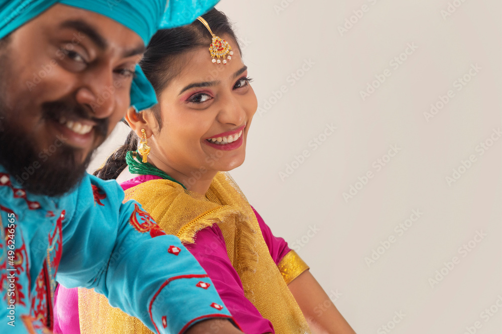 Close-up portrait of happy Sikh couple posing in front of camera during Baisakhi celebration Close-up portrait of happy Sikh couple posing in front of camera during Baisakhi celebration