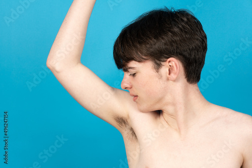 Cute boy smelling underarm. Bad odor and body hair growing on puberty