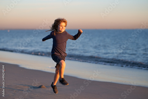 Child running through water close to shore along the sea beach. A boy runs along the sea coast. Rest of children on summer vacation. Summer vacation with child.