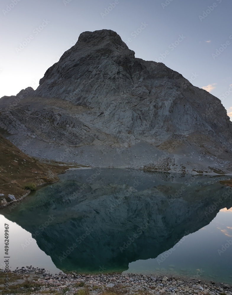 Panoramic shot of a soft reflection of an Alpine mountain in Wolayer Lake, Austria. Completely still surface of the lake. Mountain is surrounded by morning haze. Peace of mind, calmness.
